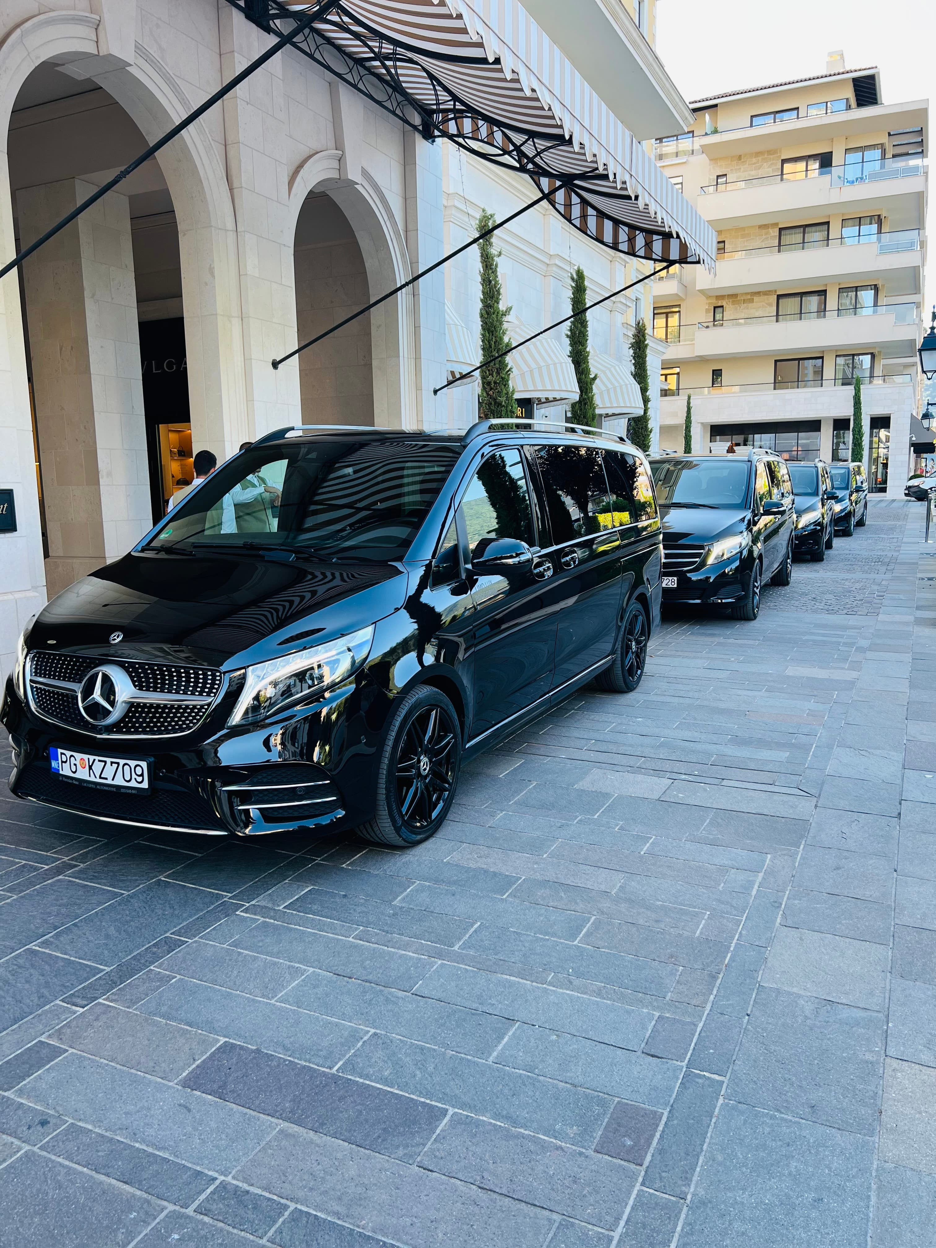 Crni Mercedes-Benz kombiji parkirani ispred ulaza u luksuzni hotel
