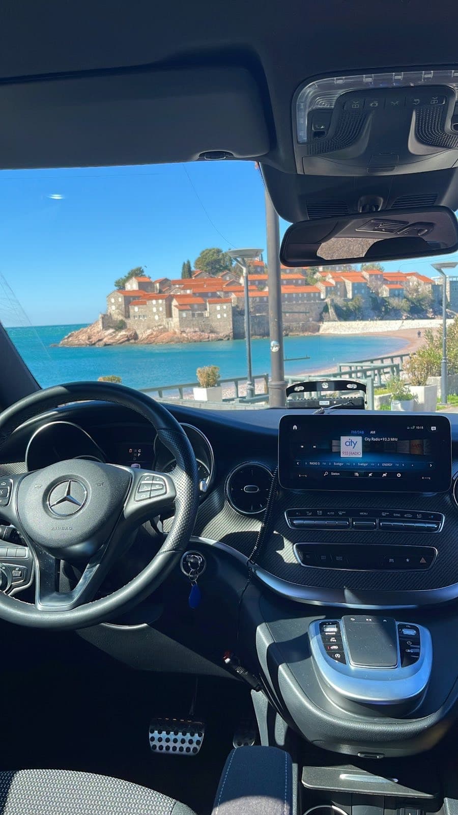Unutrašnjost Mercedes-Benz kombija sa pogledom na primorski grad kroz vjetrobran