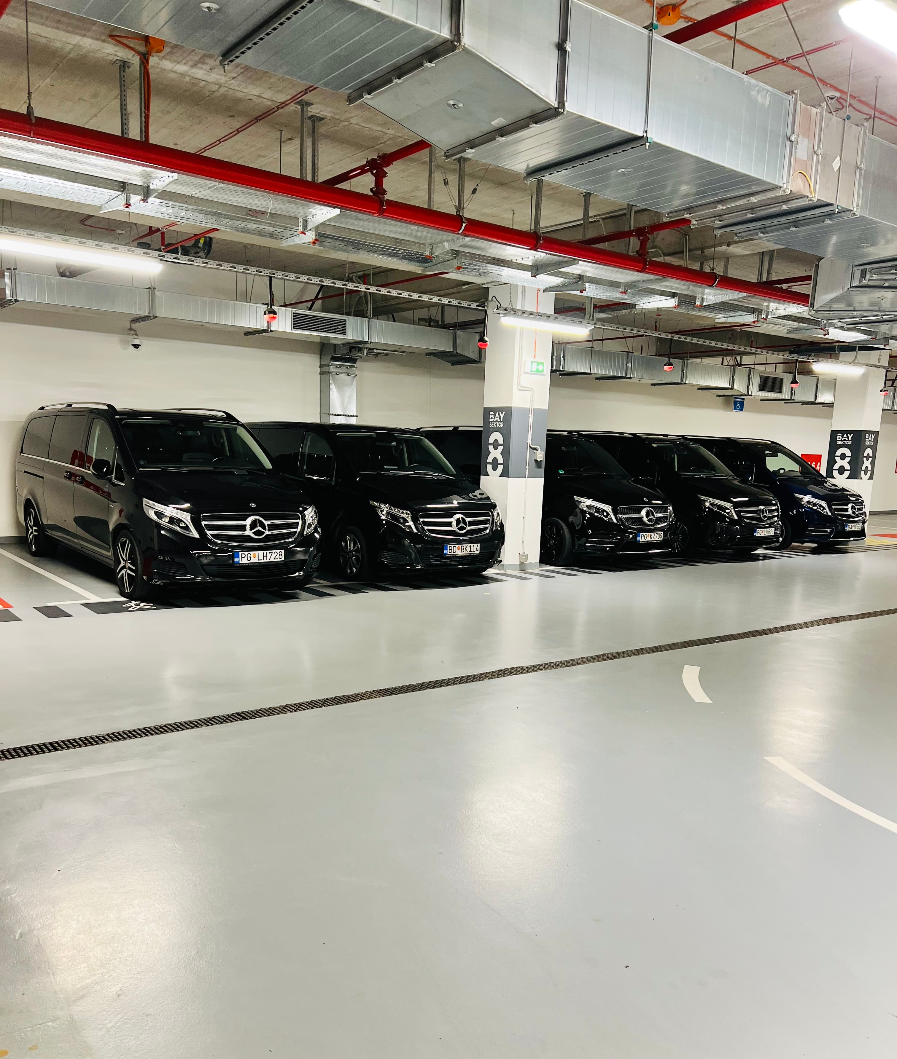 Red crnih Mercedes-Benz kombija parkiranih u zatvorenoj garaži, pogled iz šireg ugla